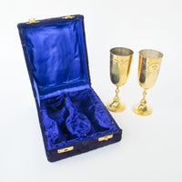 Two matching brass champagne flutes in a blue velvet box