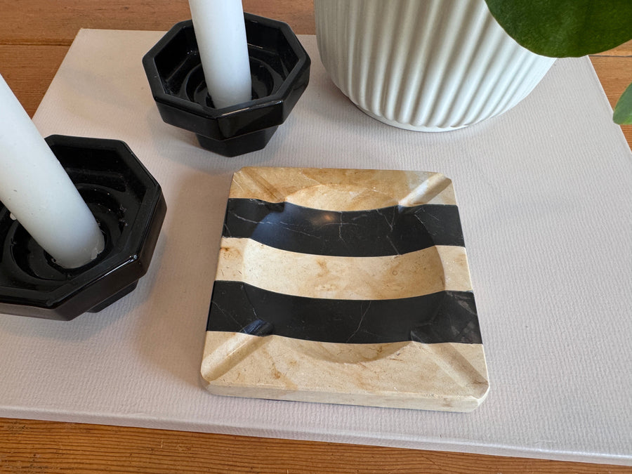Marble coaster with black stripes on a table with candles and a vase.